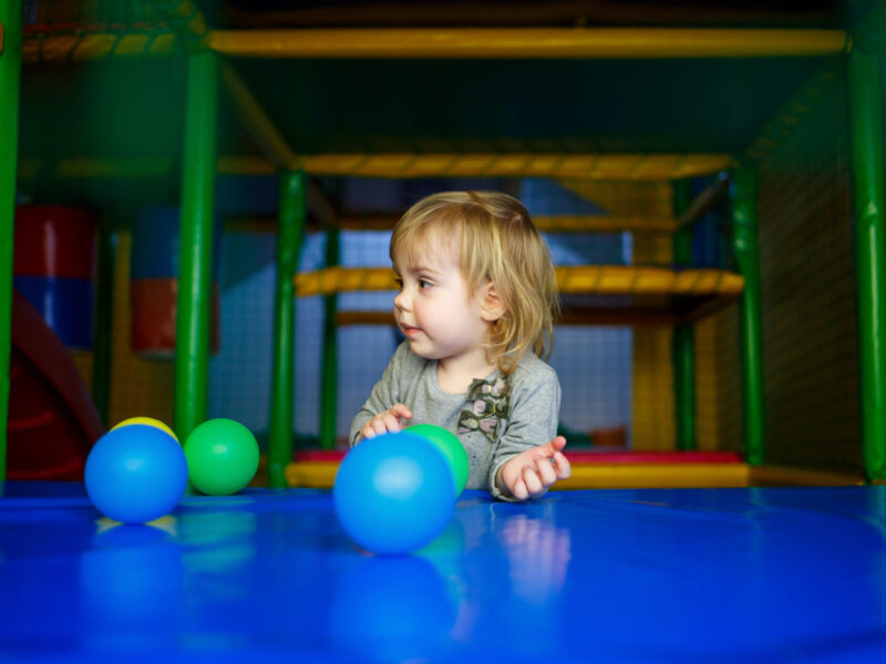 little girl 2 years old plays in a children's area with attractions